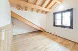 Discover this charming attic room featuring exposed wooden beams and a sloped ceiling, creating a cozy and rustic ambiance.