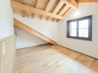 Discover this charming attic room featuring exposed wooden beams and a sloped ceiling, creating a cozy and rustic ambiance.