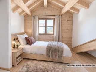 Experience cozy mountain living in this charming bedroom featuring a comfortable bed adorned with plush bedding and a decorative accent pillow.