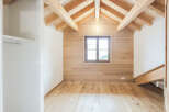 Experience rustic charm in this unfinished attic room, featuring a stunning exposed wooden beam ceiling and warm, wood-paneled walls.