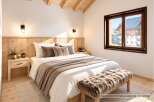 Experience cozy mountain living in this charming bedroom, featuring a comfortable bed adorned with plush throws and pillows.