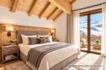 Experience luxury mountain living in this stunning bedroom, featuring a cozy king-sized bed adorned with plush pillows and a warm throw blanket.