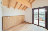 Experience the charm of alpine living in this beautifully appointed room featuring a vaulted wooden beam ceiling and warm, natural wood paneling.