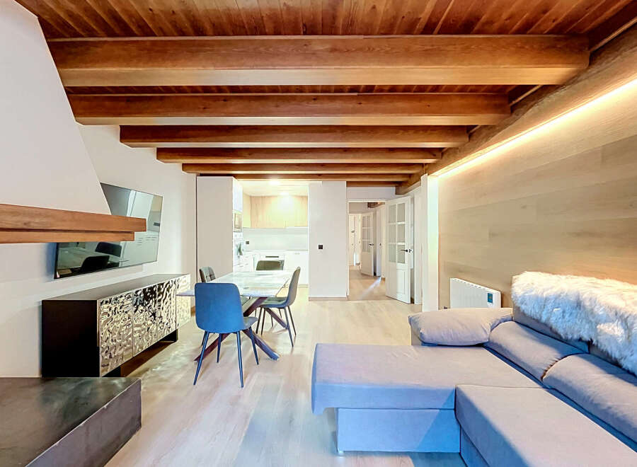 Experience modern living in this stunning open-plan space featuring exposed wooden beams and elegant wood-paneled walls.
