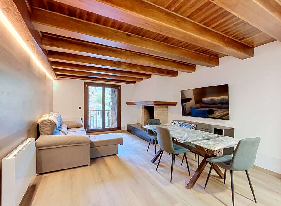 Experience rustic charm and modern comfort in this inviting living space, featuring a stunning exposed wooden beam ceiling and a cozy fireplace.