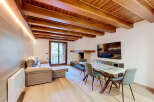 Experience rustic charm and modern comfort in this inviting living space, featuring a stunning exposed wooden beam ceiling and a cozy fireplace.