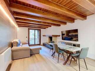 Experience rustic charm and modern comfort in this inviting living space, featuring a stunning exposed wooden beam ceiling and a cozy fireplace.