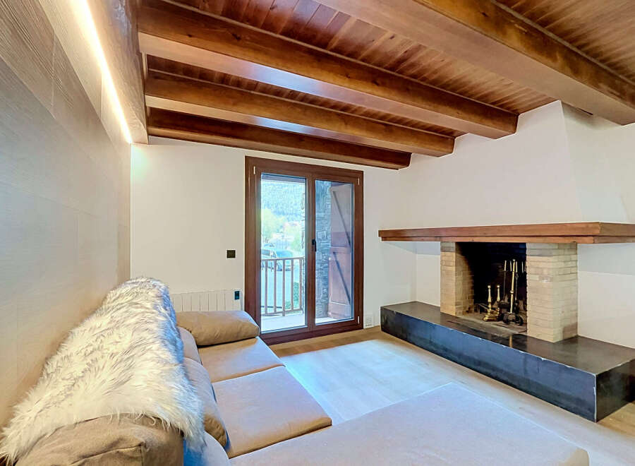 Experience rustic charm and modern comfort in this inviting living space, featuring exposed wooden beams and a cozy fireplace.