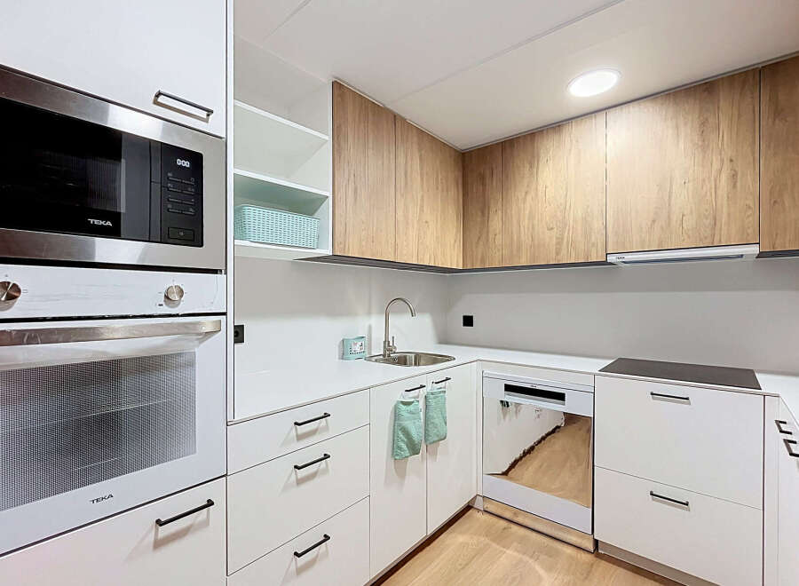 Discover this modern and functional kitchen, featuring sleek white cabinetry complemented by warm wood-grain upper cabinets.