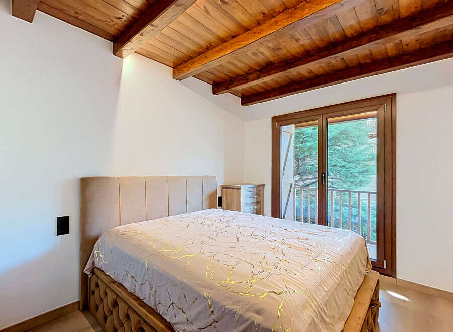 Experience rustic charm and modern comfort in this inviting bedroom, featuring exposed wooden beams and a plush upholstered bed.