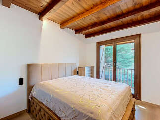 Experience rustic charm and modern comfort in this inviting bedroom, featuring exposed wooden beams and a plush upholstered bed.