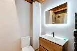 This modern bathroom features a sleek wooden vanity with a white undermount sink and a minimalist black faucet.