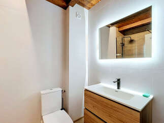 This modern bathroom features a sleek wooden vanity with a white undermount sink and a minimalist black faucet.
