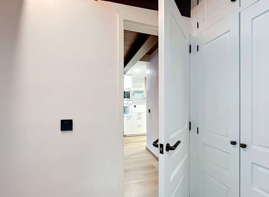 Step into a modern and inviting hallway featuring sleek white doors with elegant black hardware.