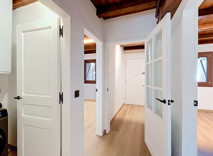 Step into this beautifully renovated hallway, featuring elegant white doors and exposed wooden beams that add rustic charm.