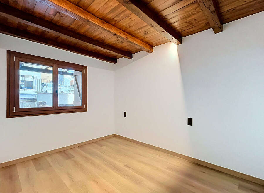 Experience rustic charm in this beautifully renovated room featuring exposed wooden beams and a warm, inviting atmosphere.