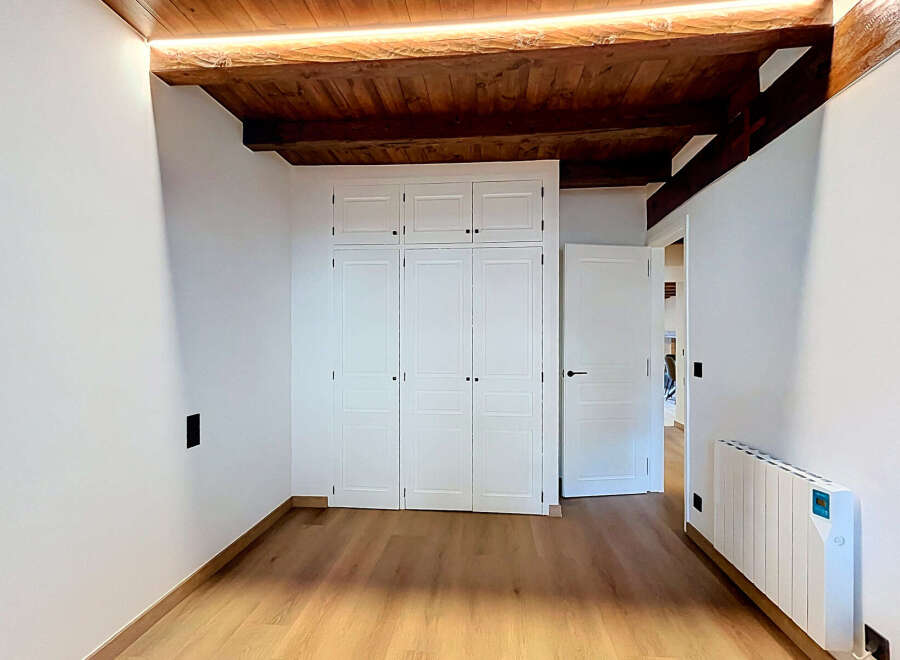 Discover this charming room featuring a built-in white wardrobe with multiple doors, perfect for ample storage.