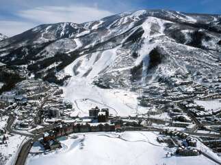 Experience the ultimate mountain lifestyle with this stunning aerial view of a ski resort village nestled at the base of majestic, snow-covered peaks.
