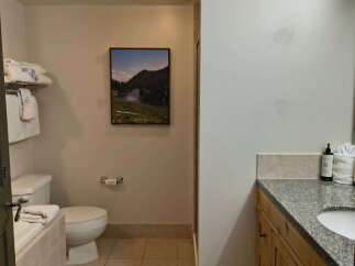 This well-appointed bathroom features a spacious bathtub, a modern toilet, and a granite-topped vanity with ample storage.