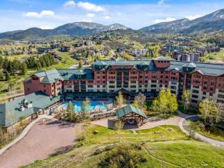 Experience luxury mountain living at this stunning resort, featuring a sprawling complex with a vibrant pool area and an inviting outdoor pavilion.
