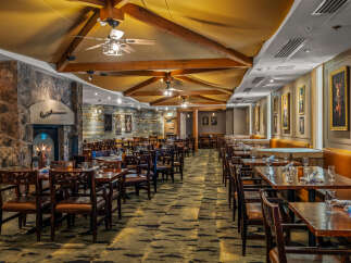 Experience rustic elegance in this dining room, featuring a grand stone fireplace and warm wooden beams.