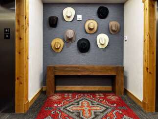 Experience rustic charm with this inviting entryway, featuring a collection of cowboy hats displayed above a sturdy wooden bench.