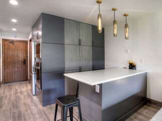 Discover modern living in this stylish kitchen featuring sleek grey cabinetry and a pristine white quartz countertop island.