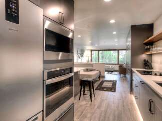 Experience modern living in this stylish studio apartment, featuring a sleek stainless steel kitchen with integrated appliances and ample cabinet space.
