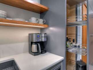 Discover a modern kitchen with sleek grey cabinetry and warm wooden shelving, perfect for displaying decorative items and storing essentials.
