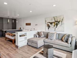 Discover this stylish studio apartment featuring a modern sectional sofa and a unique abstract art piece of a bull.