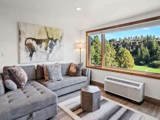 Experience breathtaking views from this living room, featuring a large sectional sofa and a striking abstract art piece.
