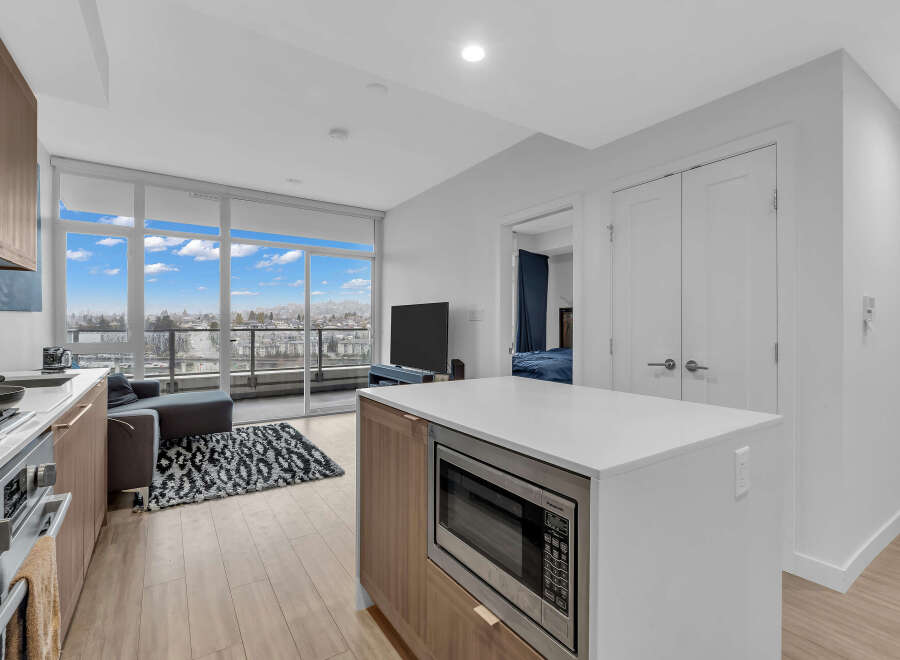 Experience modern living in this stunning condo featuring a sleek kitchen with a microwave island and a spacious living area with a balcony overlooking the city.