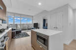 Experience modern living in this stunning condo featuring a sleek kitchen with a microwave island and a spacious living area with a balcony overlooking the city.