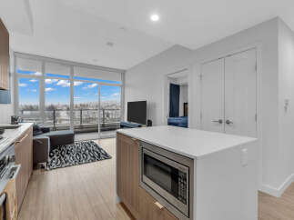 Experience modern living in this stunning condo featuring a sleek kitchen with a microwave island and a spacious living area with a balcony overlooking the city.