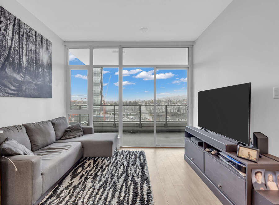 Experience modern living in this stylish condo featuring a spacious sectional sofa and a large flat-screen TV, perfect for relaxation and entertainment.
