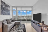 Experience modern living in this stylish condo featuring a spacious sectional sofa and a large flat-screen TV, perfect for relaxation and entertainment.