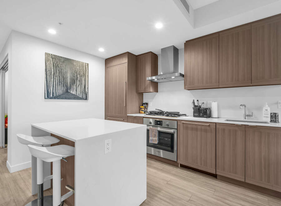 Experience modern living in this stunning kitchen, featuring sleek, dark wood cabinetry and a pristine white island with bar seating.