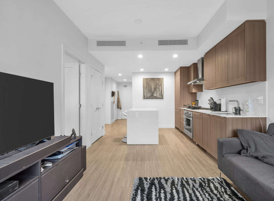 Experience modern living in this stylish apartment featuring a sleek, open-concept kitchen with rich wood cabinetry and stainless steel appliances.