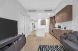 Experience modern living in this stylish apartment featuring a sleek, open-concept kitchen with rich wood cabinetry and stainless steel appliances.