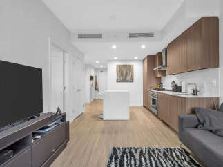 Experience modern living in this stylish apartment featuring a sleek, open-concept kitchen with rich wood cabinetry and stainless steel appliances.