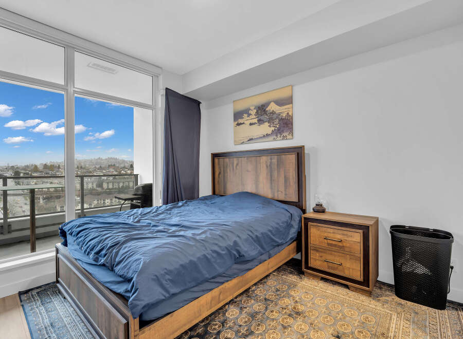 Experience modern living in this stylish bedroom featuring a comfortable bed with a rich blue duvet, complemented by a rustic wooden headboard and nightstand.