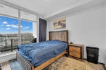 Experience modern living in this stylish bedroom featuring a comfortable bed with a rich blue duvet, complemented by a rustic wooden headboard and nightstand.