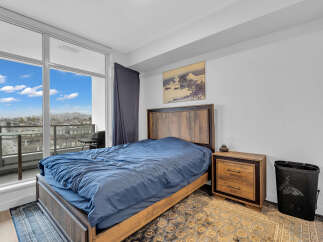 Experience modern living in this stylish bedroom featuring a comfortable bed with a rich blue duvet, complemented by a rustic wooden headboard and nightstand.