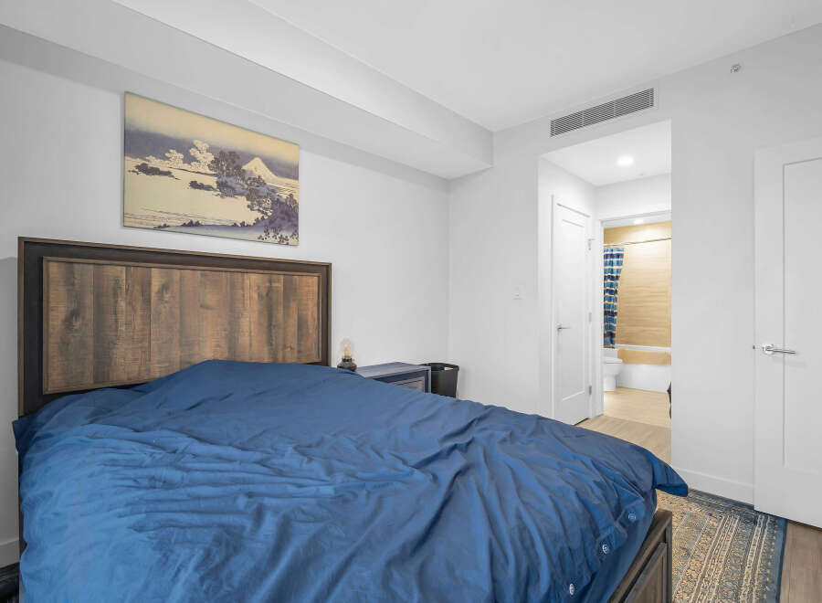 Experience comfort and style in this inviting bedroom, featuring a striking wooden headboard and a plush blue duvet.