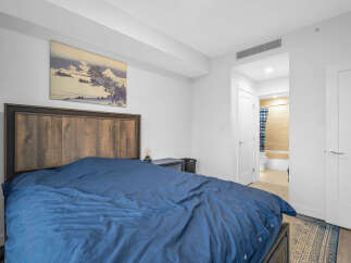 Experience comfort and style in this inviting bedroom, featuring a striking wooden headboard and a plush blue duvet.