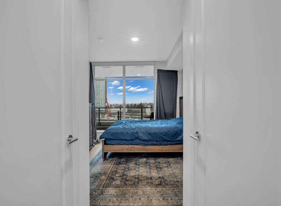 Step into this inviting bedroom featuring a plush blue comforter on a wooden bed frame, complemented by a beautifully patterned rug.