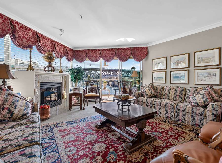 Experience luxurious living in this elegant living room, featuring a grand fireplace and ornate valances.