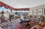 Experience luxurious living in this elegant living room, featuring a grand fireplace and ornate valances.