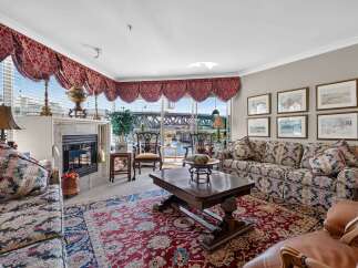 Experience luxurious living in this elegant living room, featuring a grand fireplace and ornate valances.