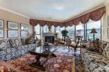 Experience luxurious living in this elegant living room, featuring a grand fireplace and plush, patterned sofas perfect for relaxation.
